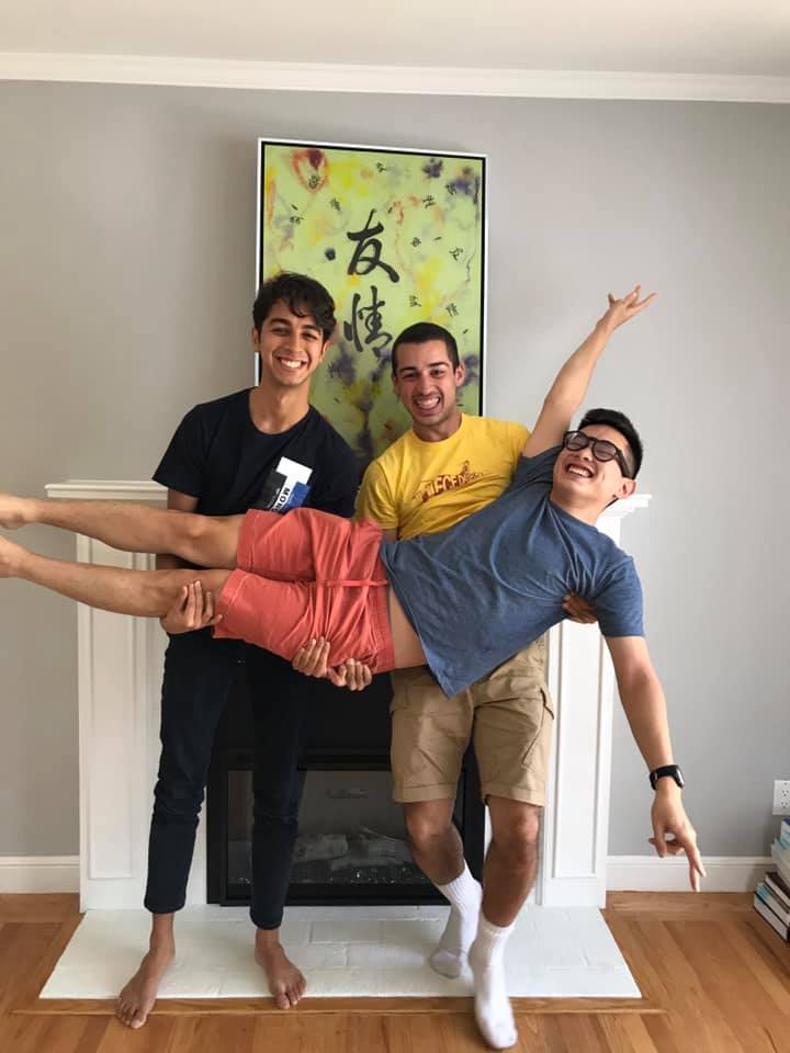 Photo of the Siempre team. Two team members are holding the third. The third looks happy. There is a painting in the background.
